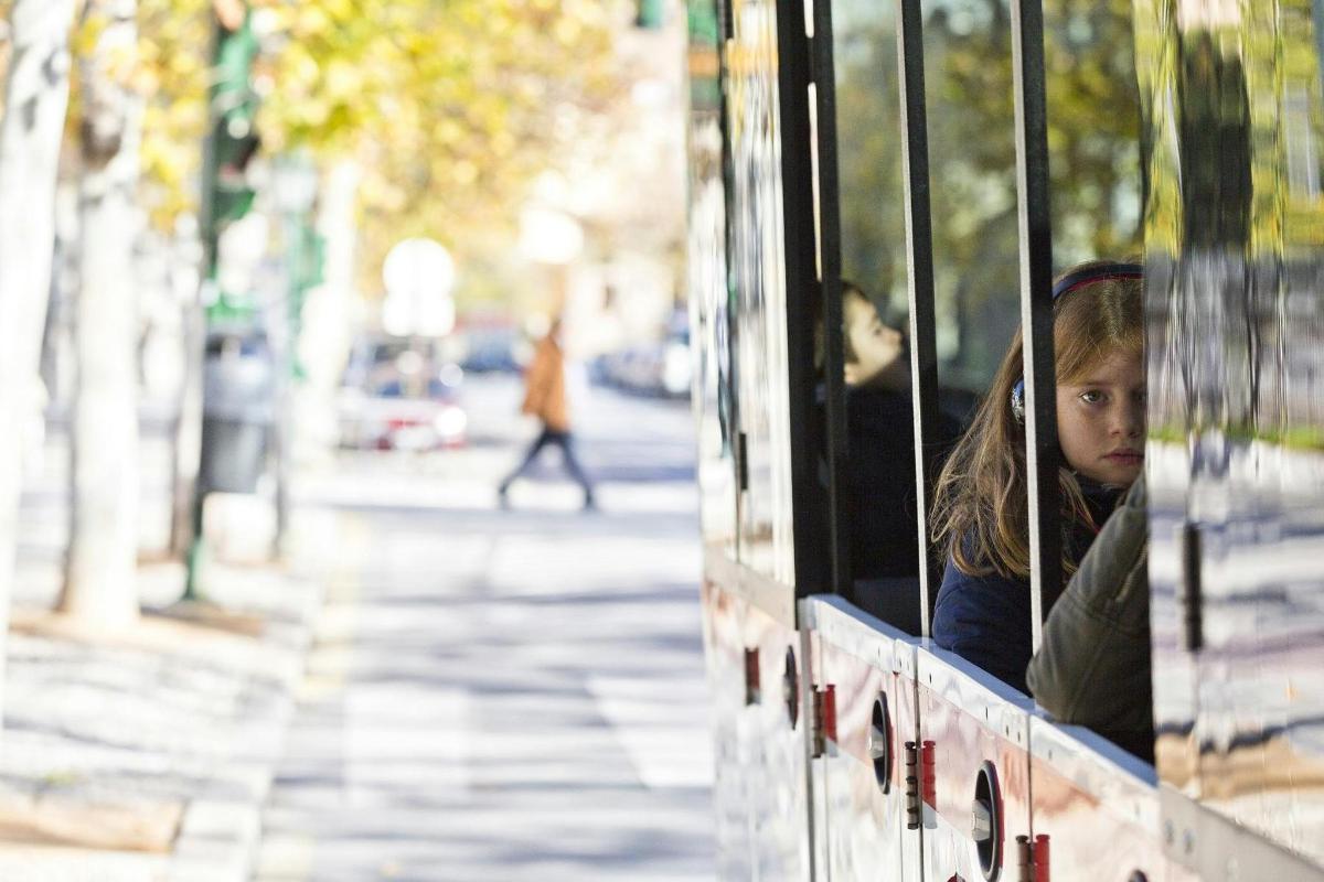 a little girl looking out the window of a bus