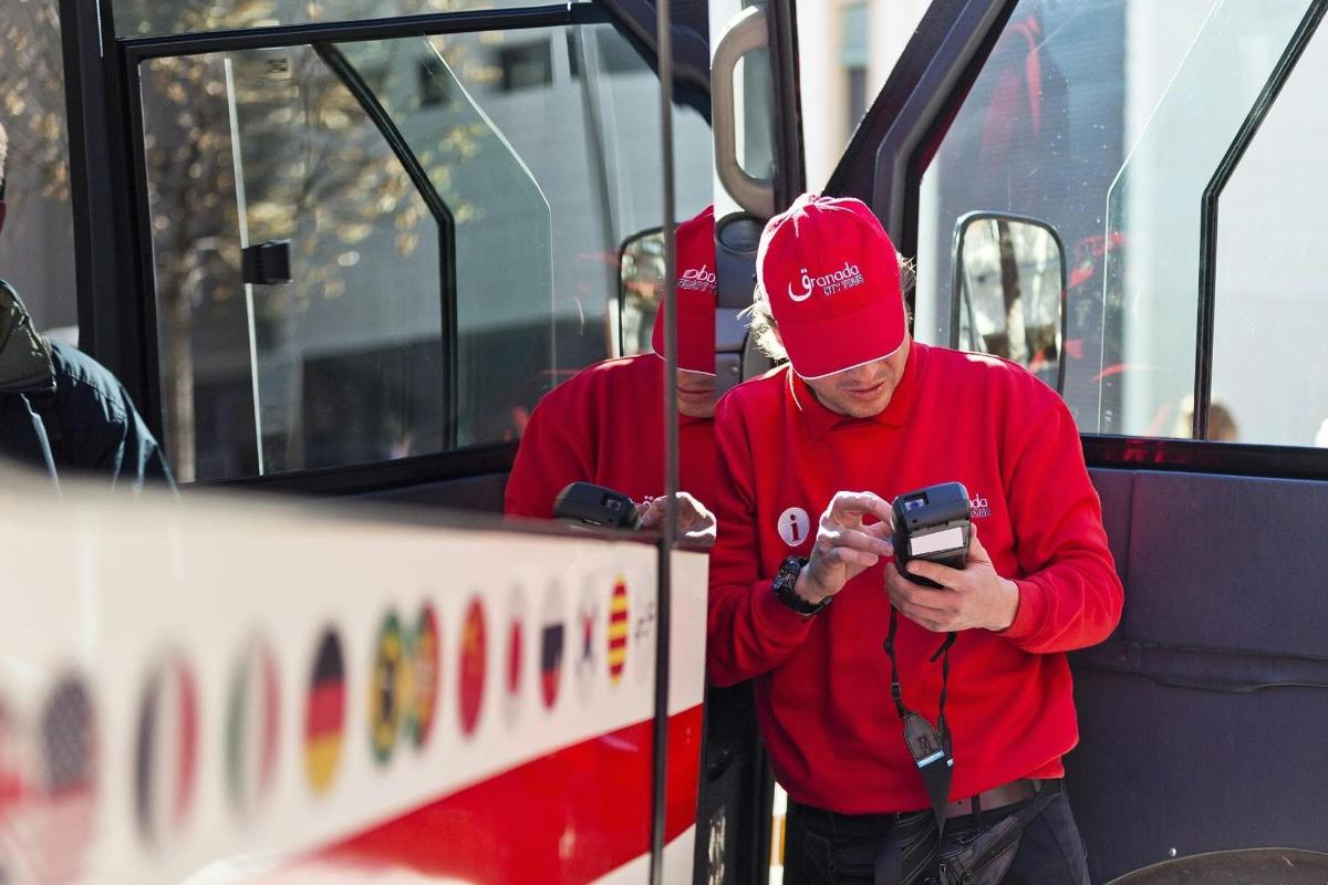 a man standing on a bus looking at his cell phone
