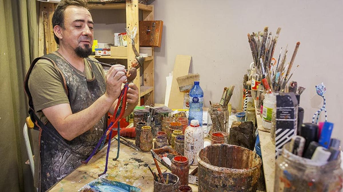 um homem está pintando um pote sobre uma mesa