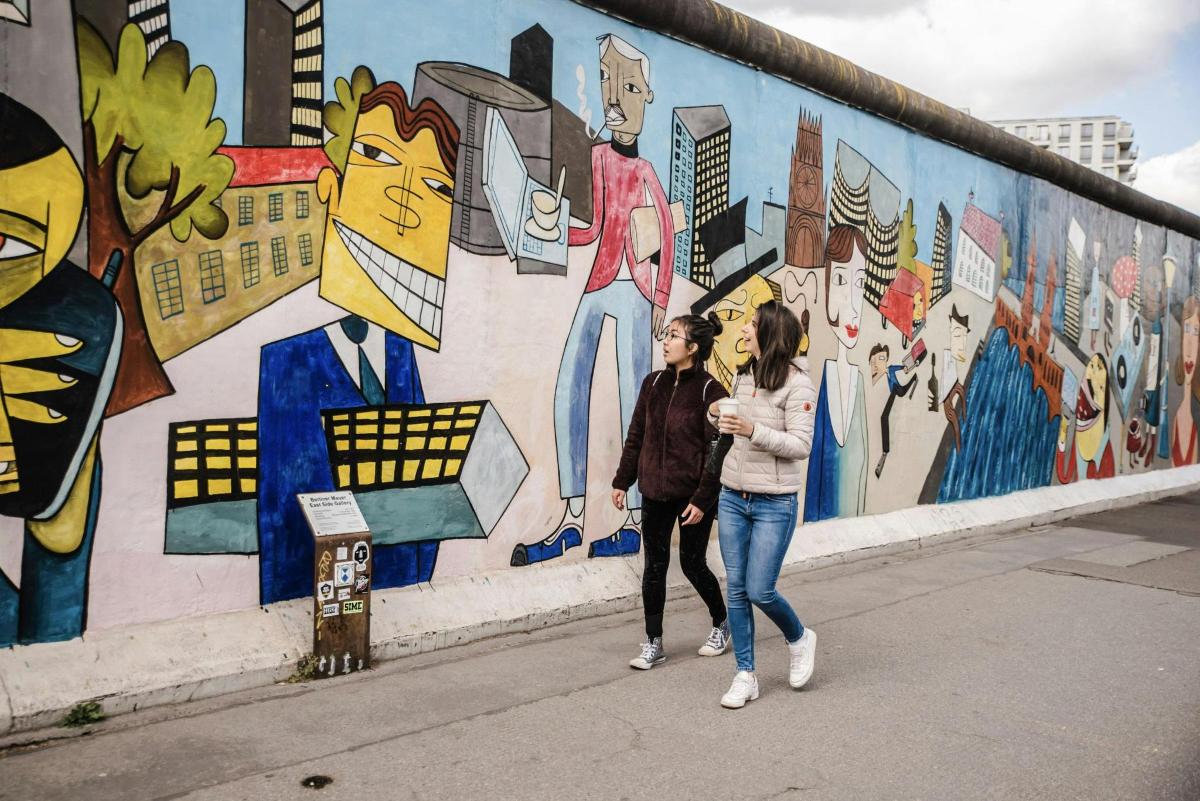 zwei Frauen gehen vor einer Wand mit einem Wandgemälde