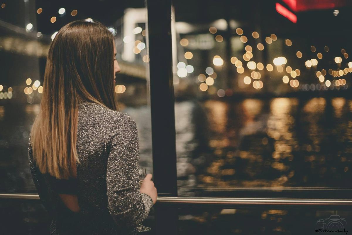 Una mujer mirando por una ventana una ciudad de noche.