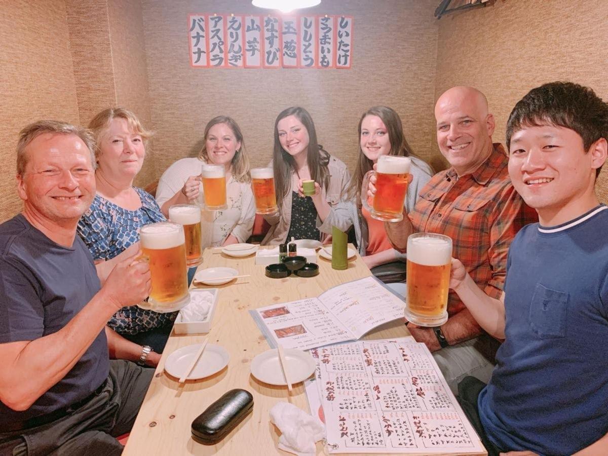 skupina lidí sedících kolem stolu a pijících pivo