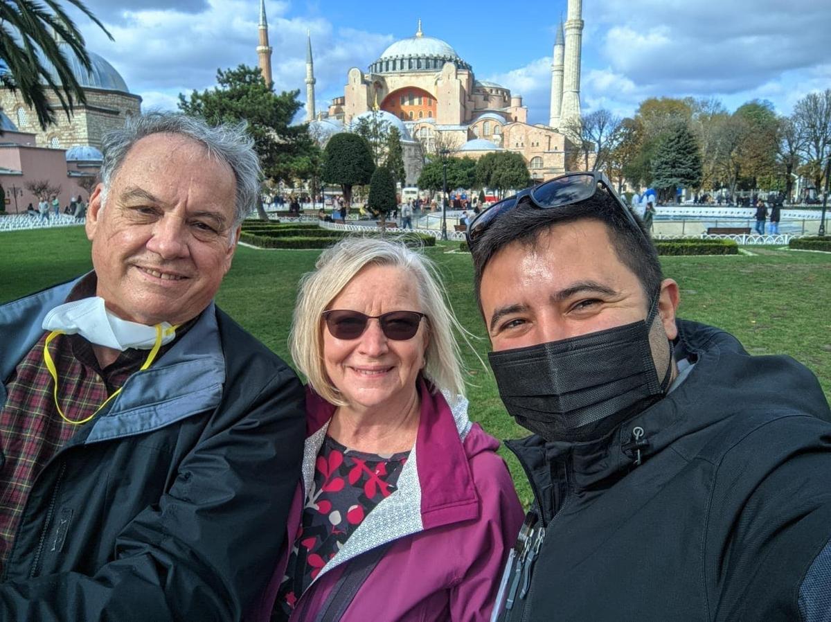 zwei Männer und eine Frau stehen vor einer Moschee