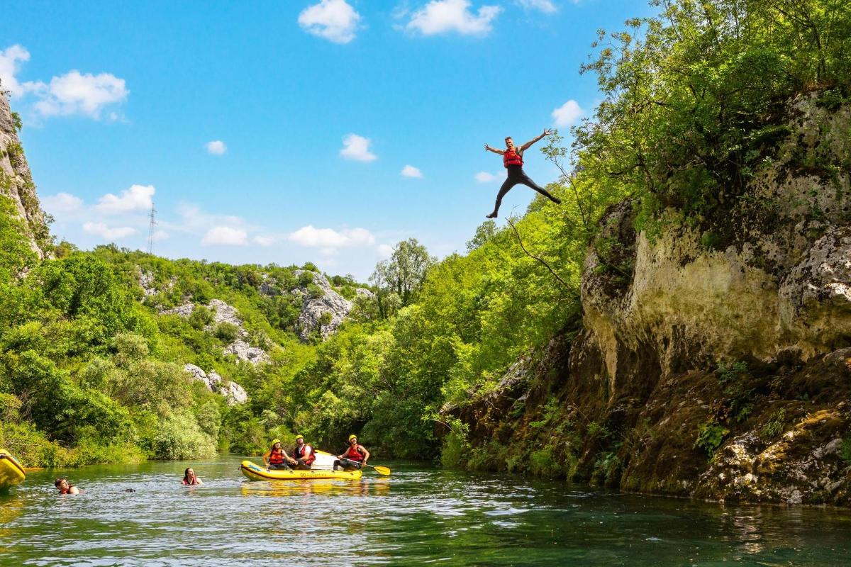 a man jumping off a cliff into a river