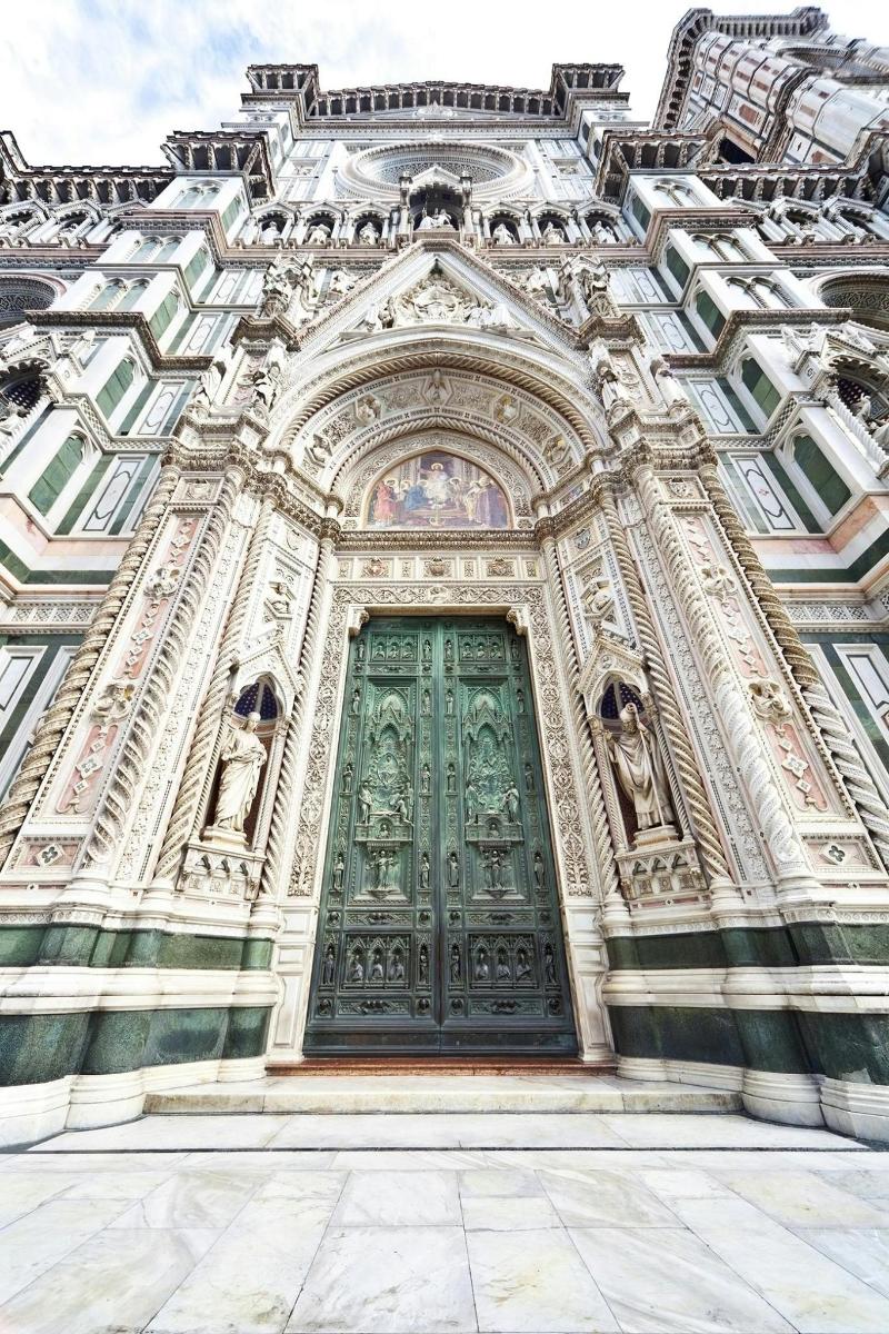 un edificio con una porta verde con delle statue sopra