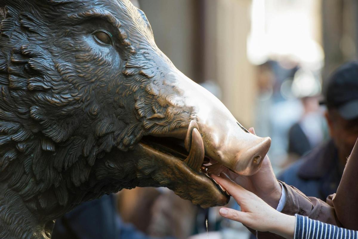 una persona che nutre con la lingua la statua di un orso