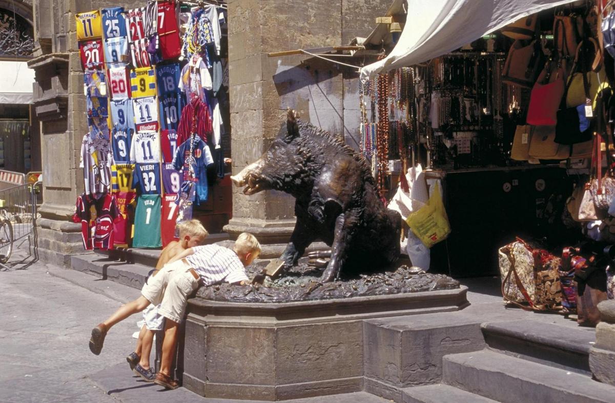 un gruppo di bambini che giocano intorno alla statua di un orso