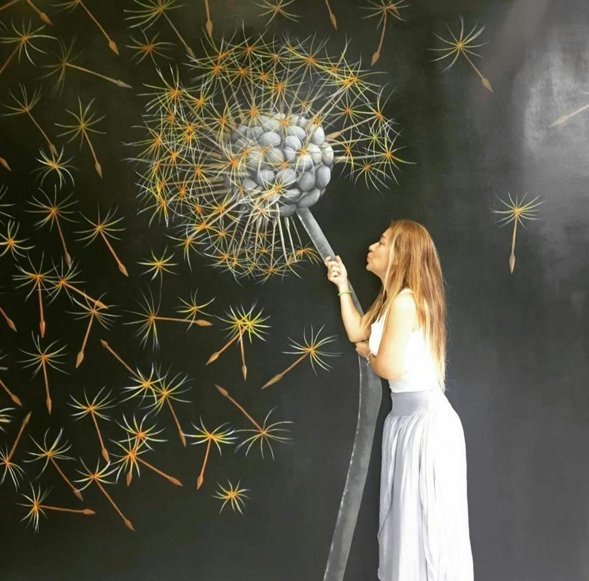 a woman is holding a dandelion in front of a painting