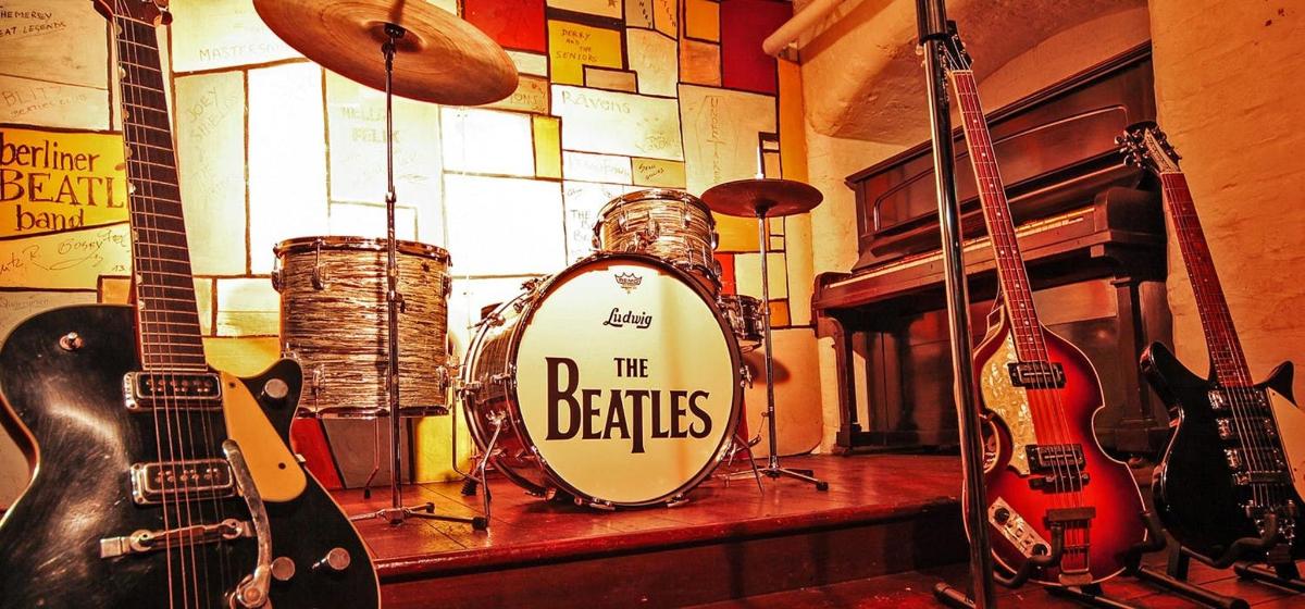 a drum set with the beatles on it in a room with guitars