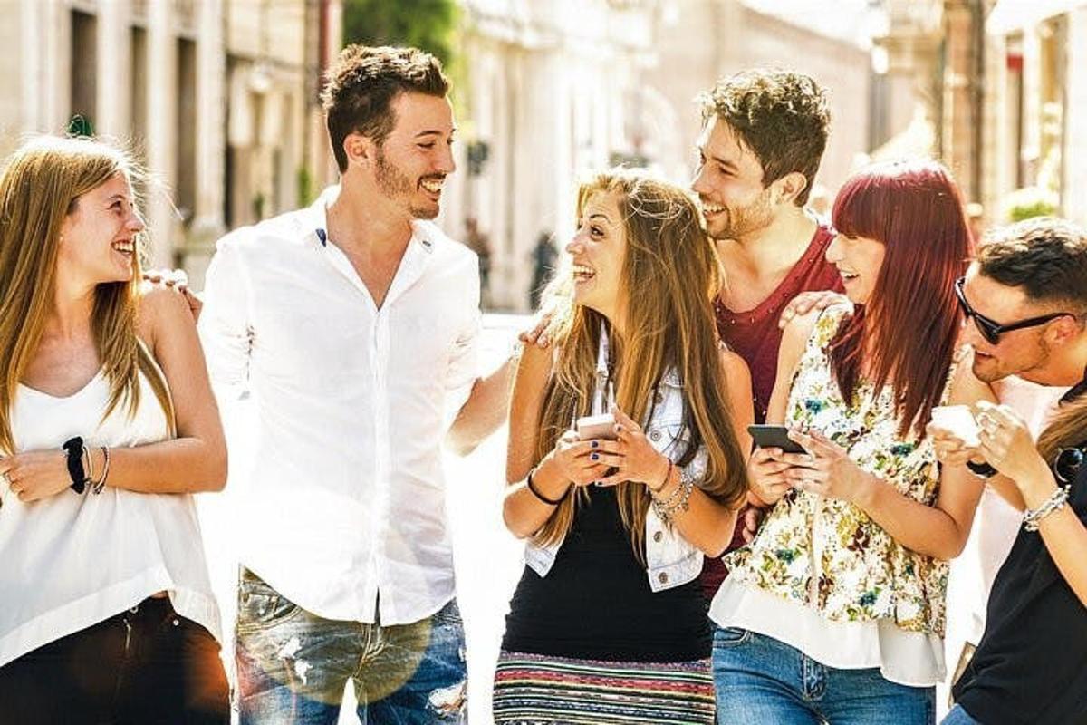 um grupo de pessoas caminhando pela rua olhando para seus celulares