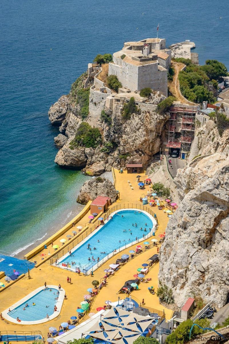 a group of swimming pools on a cliff next to the ocean