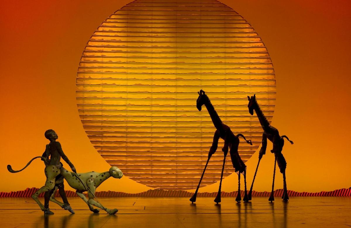 three figurines of three giraffes and a lion