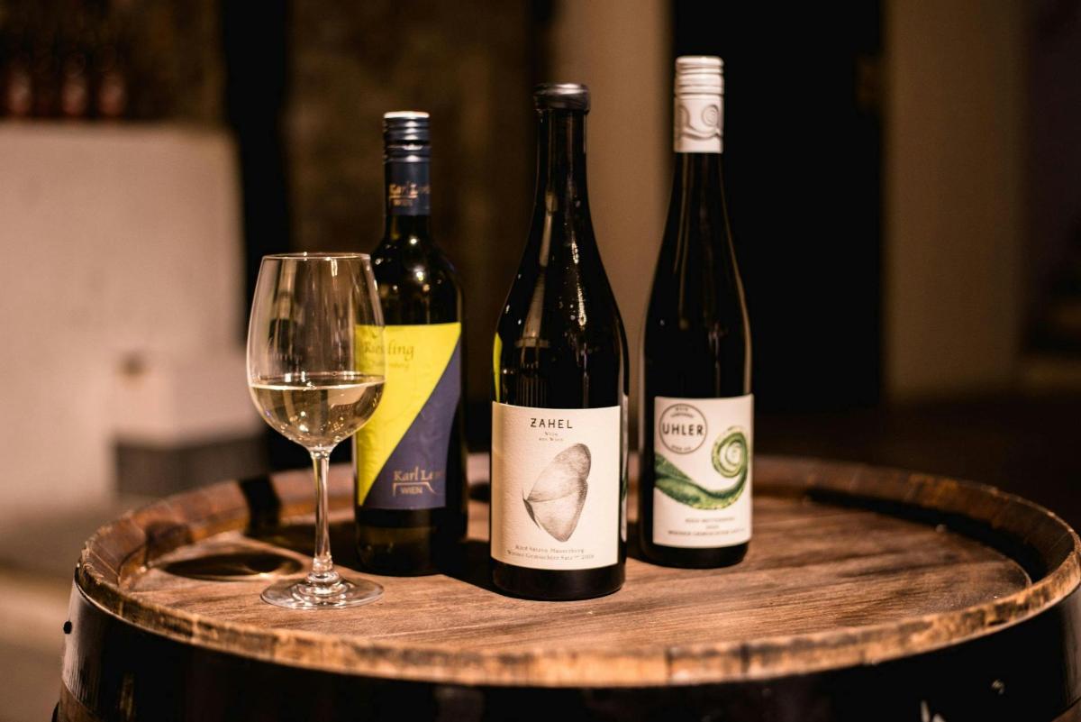 drei Flaschen Wein und ein Glas auf einem Fass