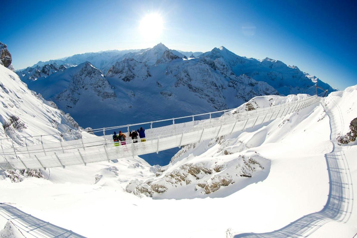 Menschen auf einer Hängebrücke auf einem schneebedeckten Berg