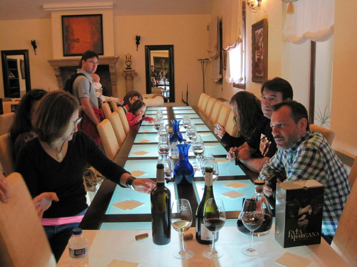 a group of people sitting around a long table with wine bottles
