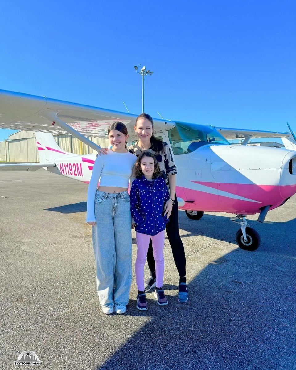 uma mulher e duas meninas em pé na frente de um avião