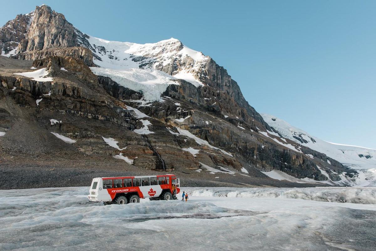 a red and white bus parked on a snow covered mountain