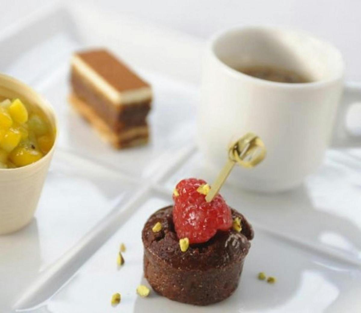 a piece of chocolate dessert on a plate with a cup of coffee
