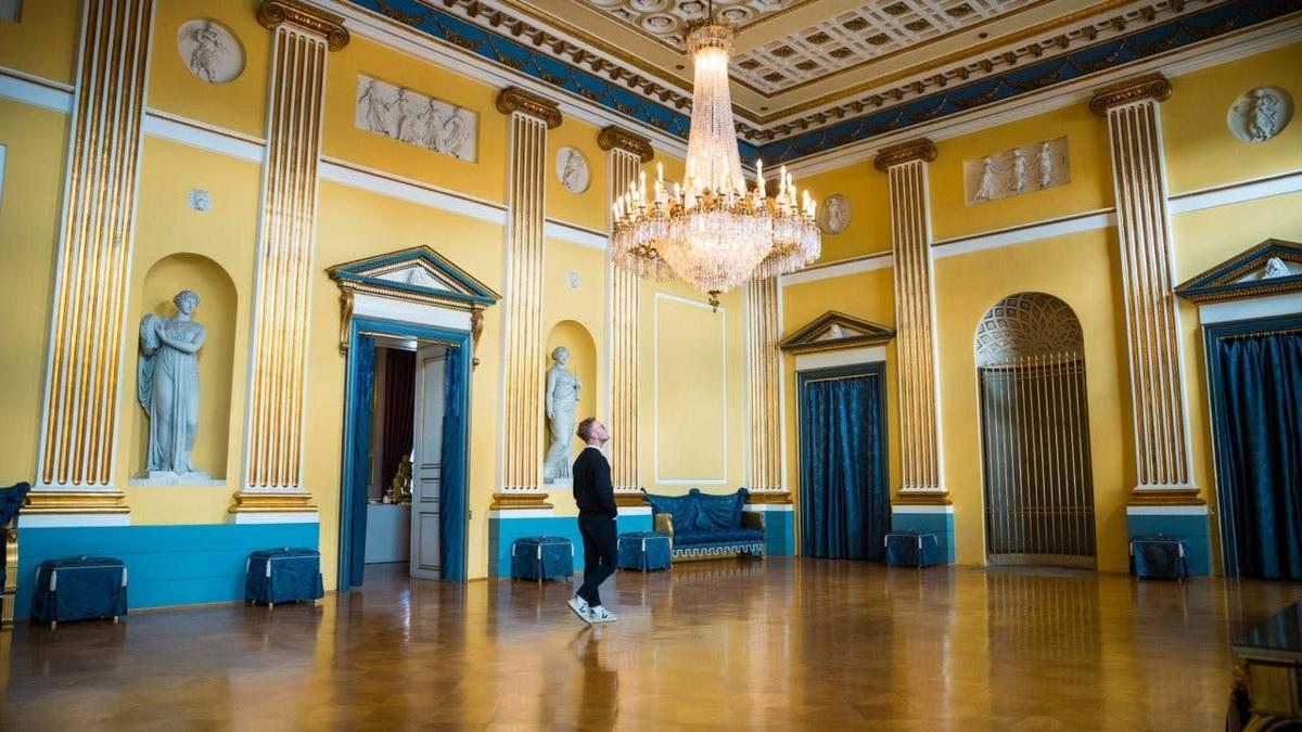 moški, ki stoji v veliki sobi z lestencem