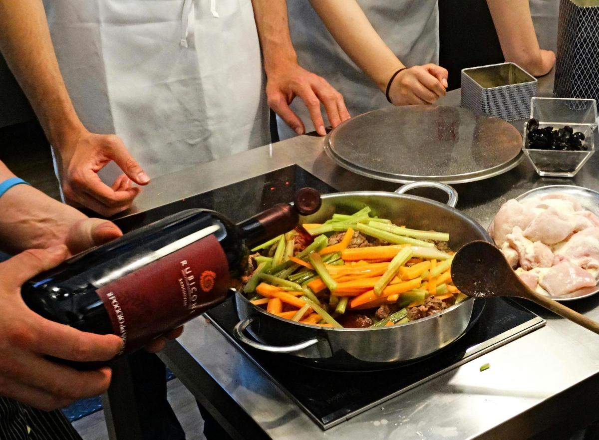 uma pessoa despejando uma garrafa de vinho em uma panela de comida