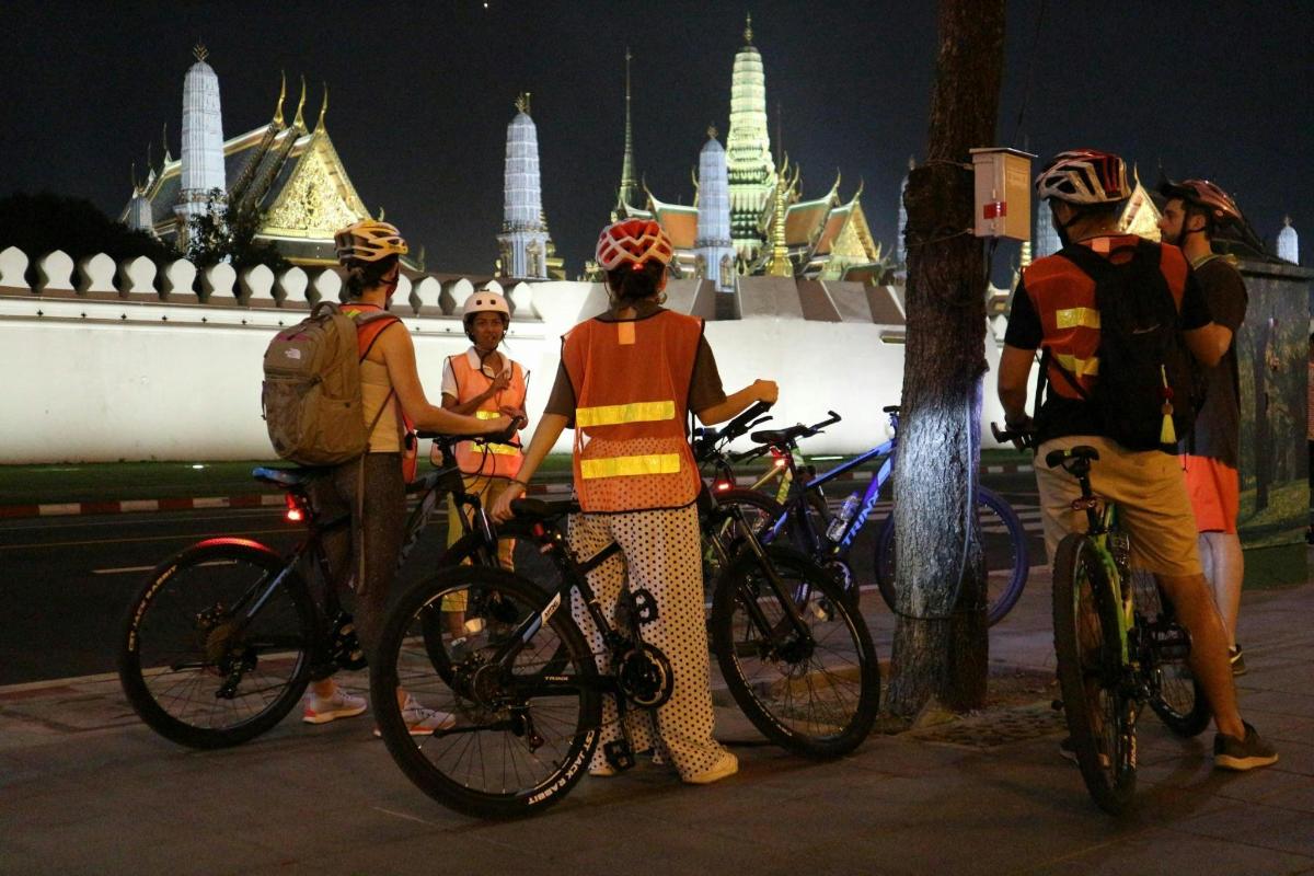 a group of people standing with bikes in front of a building