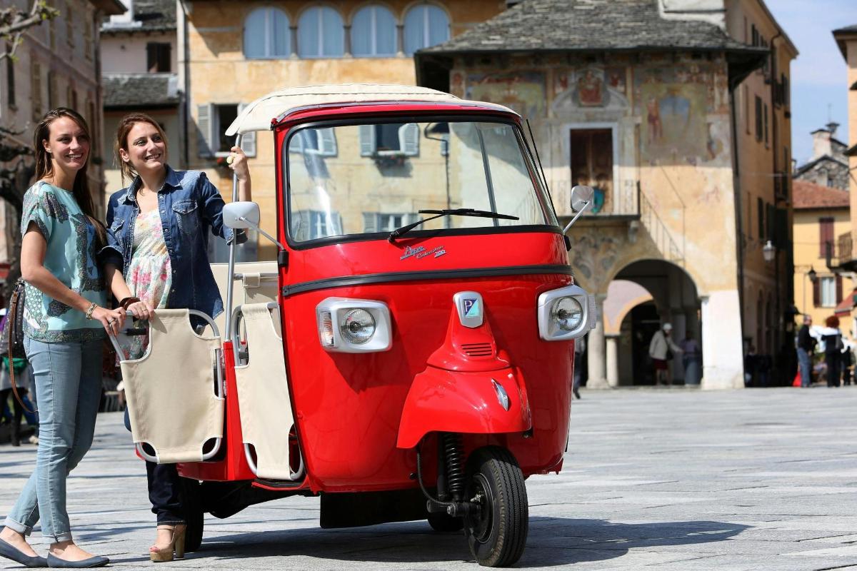 due donne sono in piedi accanto a uno scooter rosso