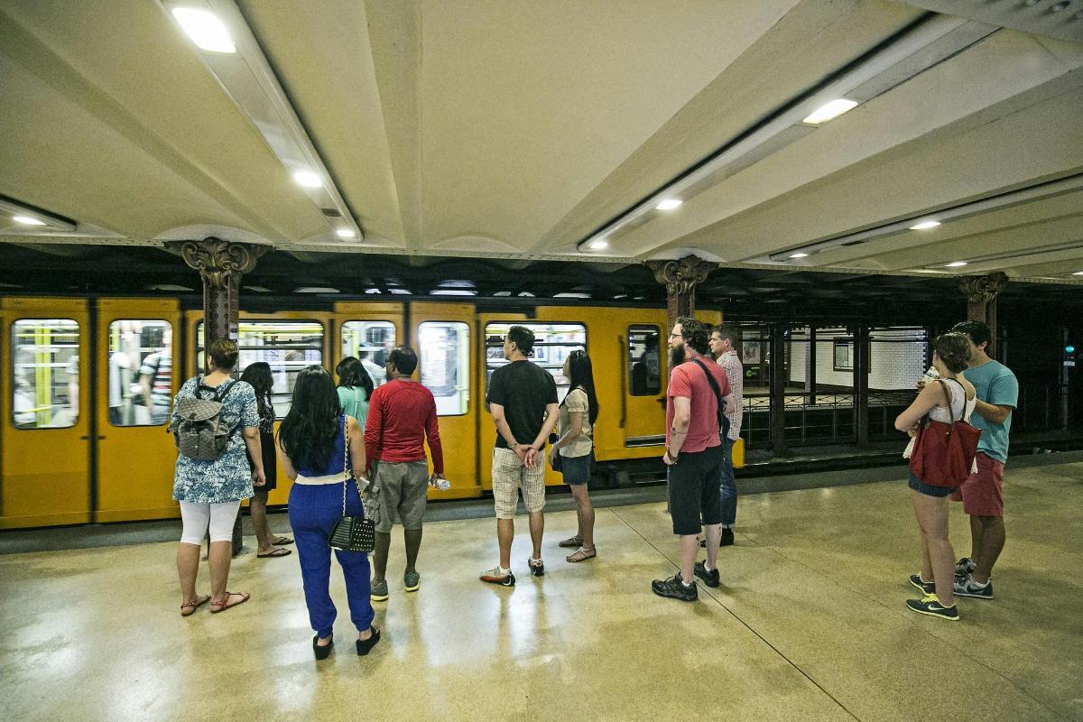 a group of people standing in front of a yellow subway train