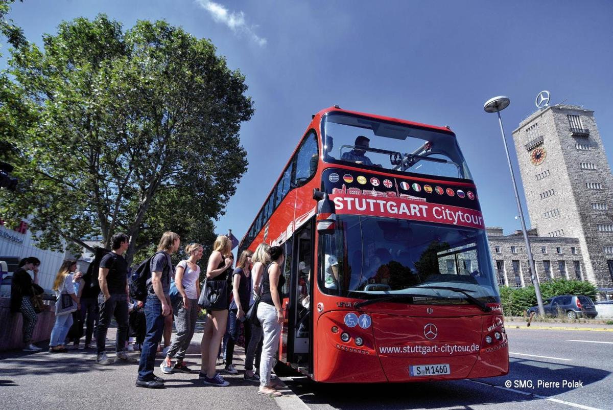 a group of people getting on a red double decker bus