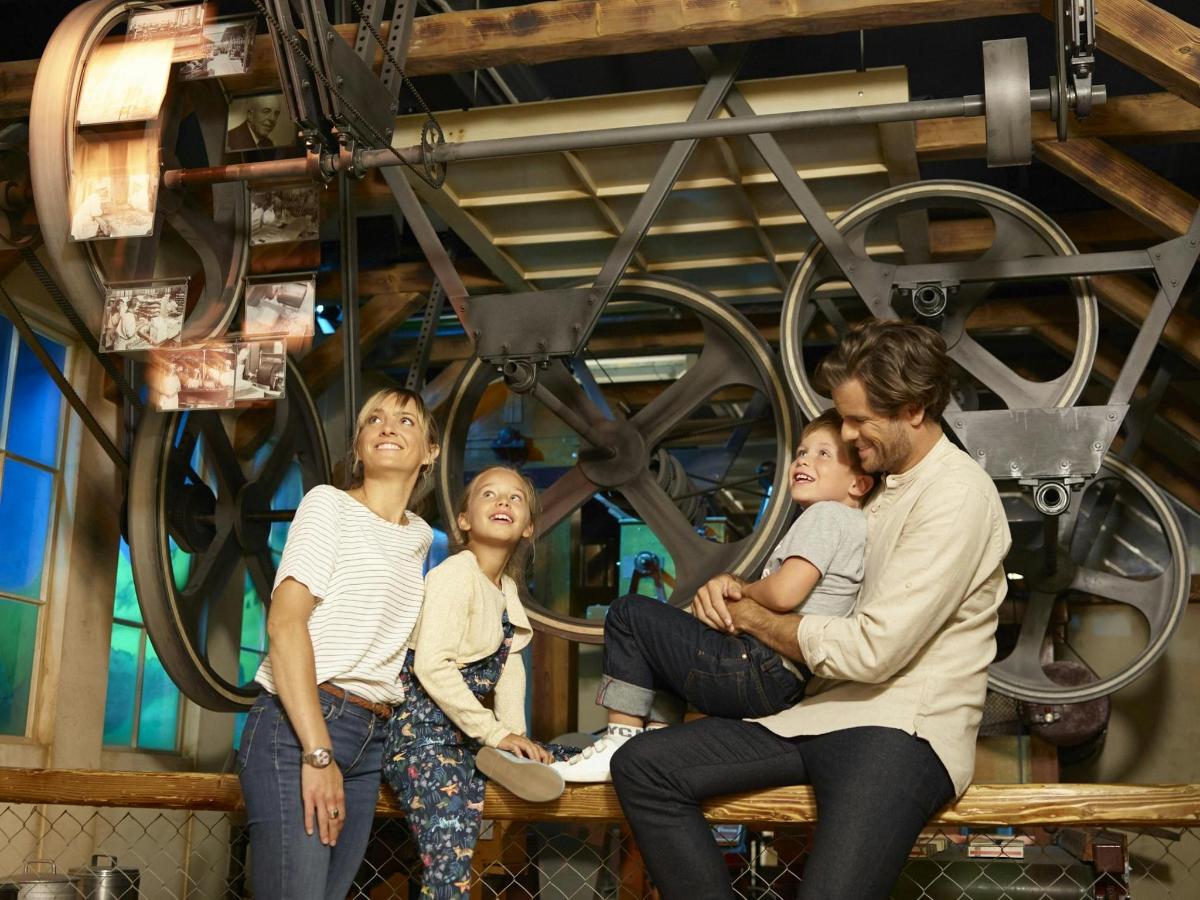a family sitting on a bench in front of a wheel