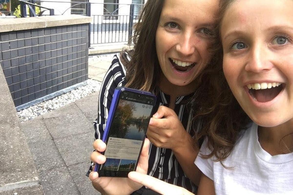 two women are holding up a cell phone
