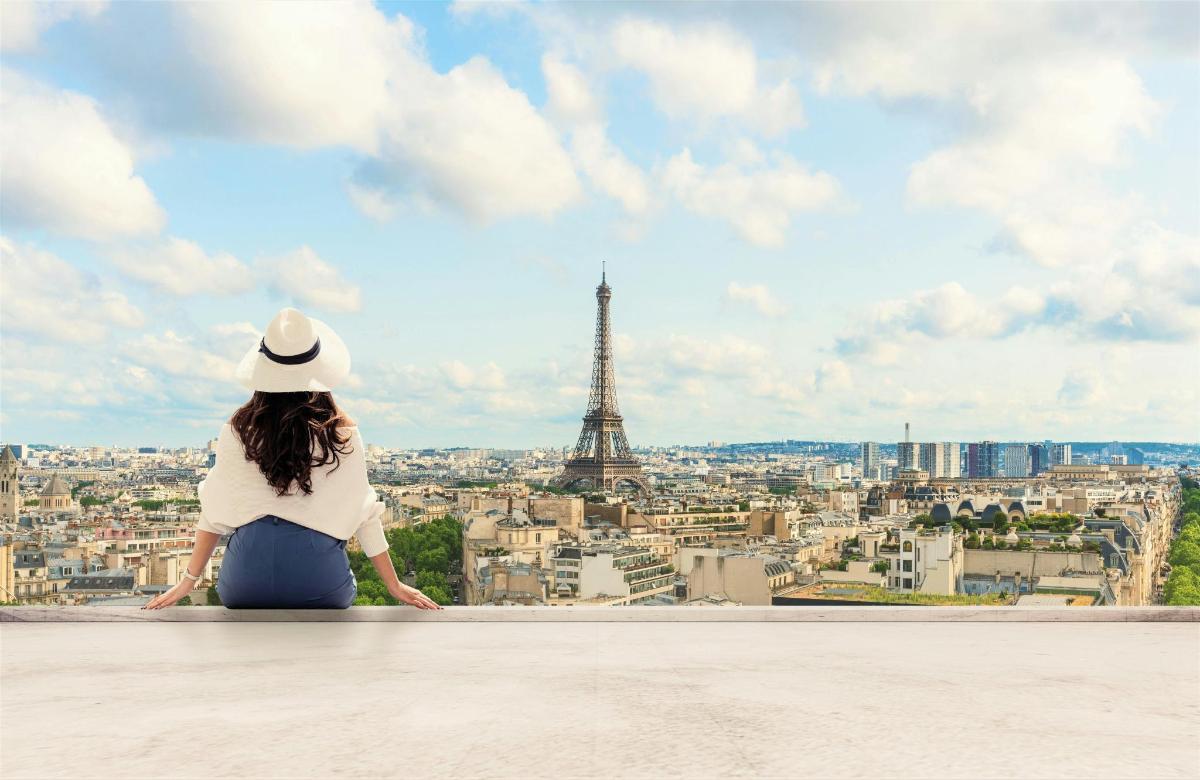 una donna seduta su una sporgenza che guarda la torre Eiffel