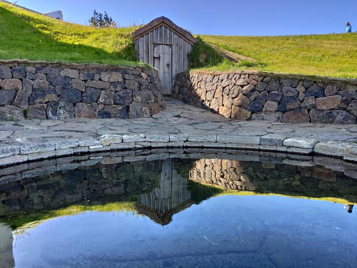 a reflection of a stone wall and a small building