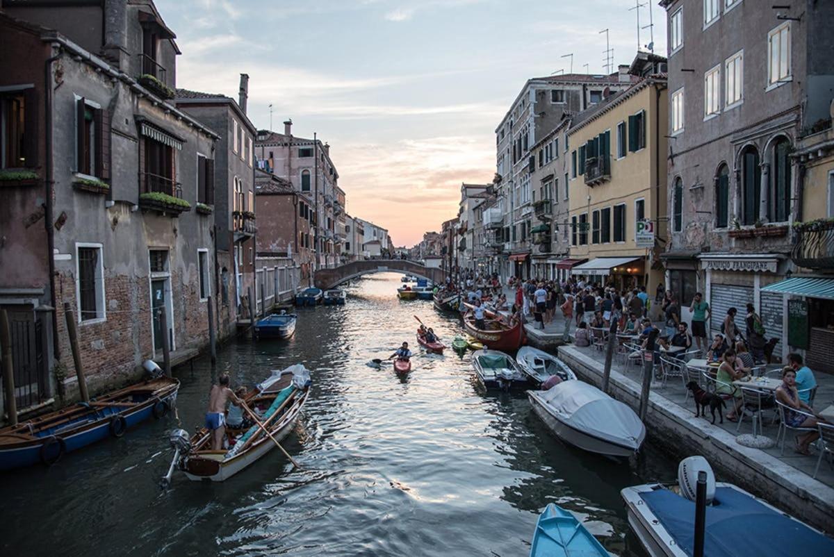 un gruppo di persone in barche in un canale con edifici