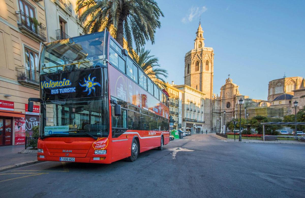 un autobús vermell de dos pisos circulant per un carrer de la ciutat