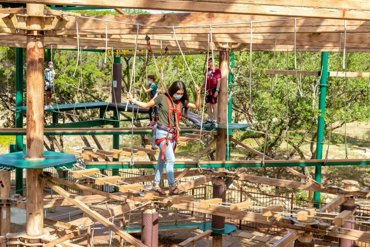 Una mujer en un circuito de cuerdas en un parque infantil.