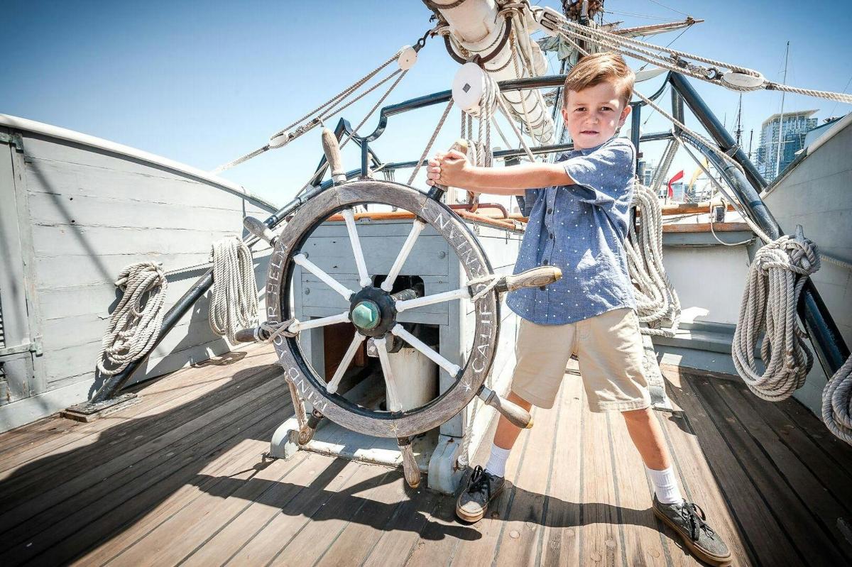a young boy standing next to a wheel on a boat