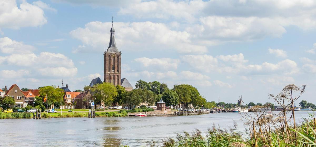 a church with a steeple on the side of a river