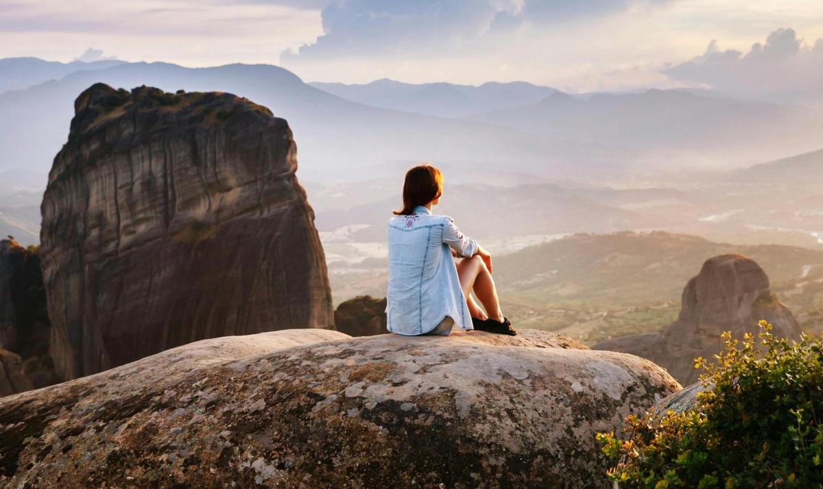una mujer sentada en una roca en una montaña