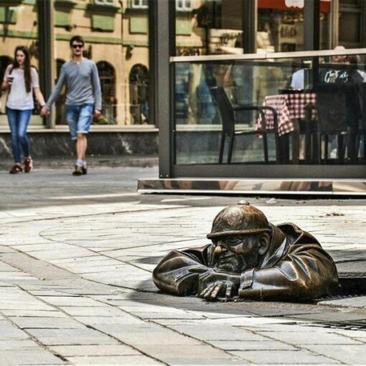 bronsstytta af manni sem liggur á götunni