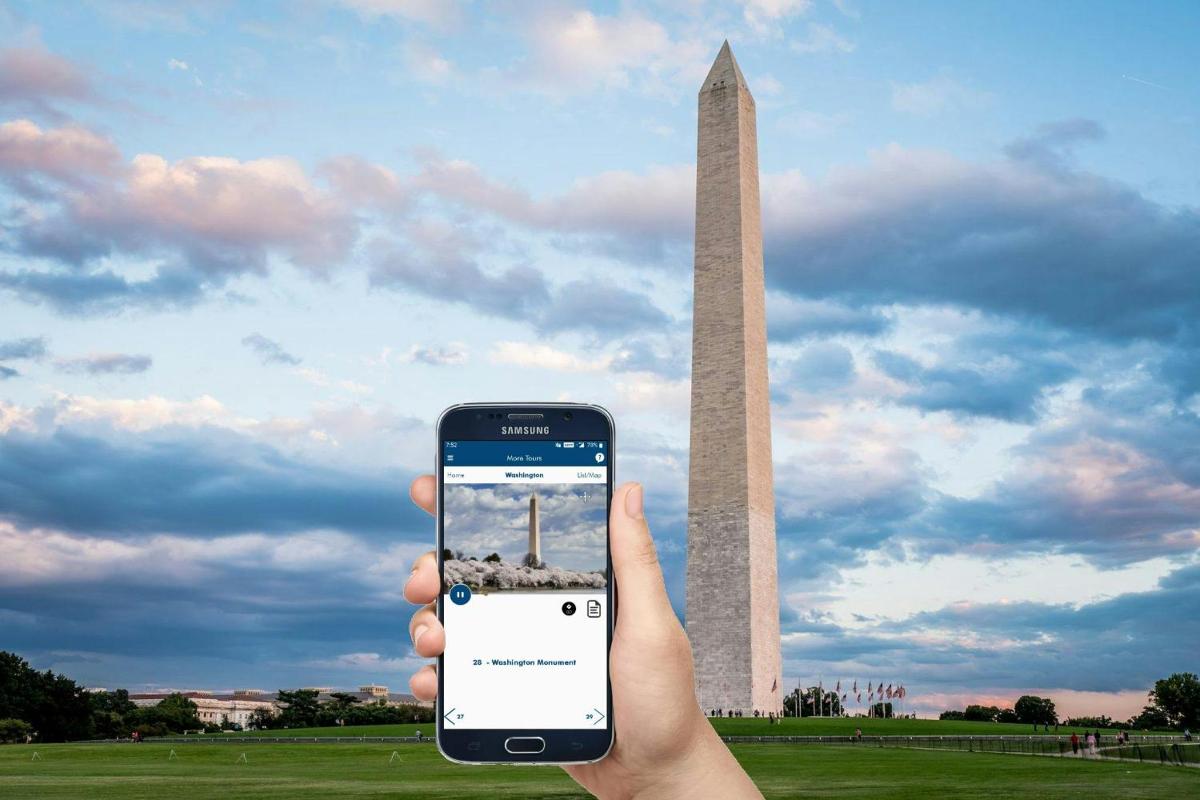 osoba držící mobilní telefon před Washingtonským monumentem
