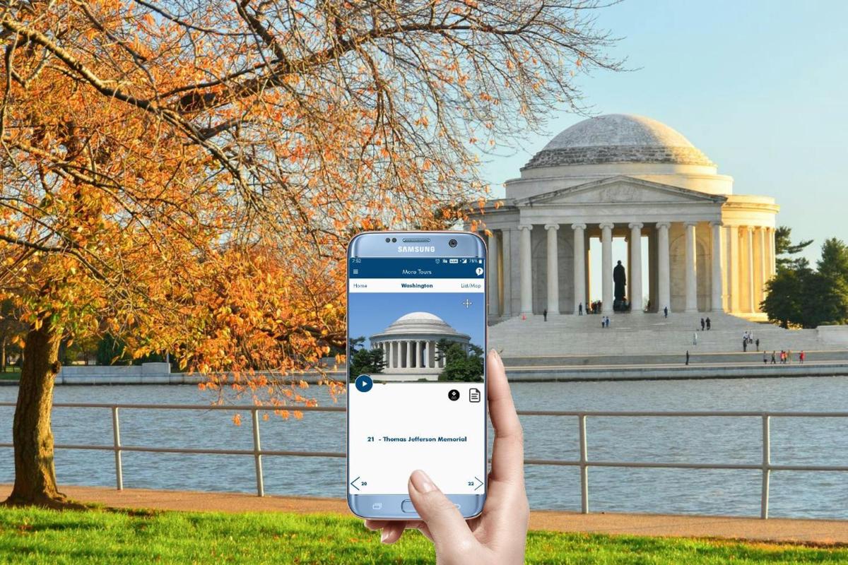 osoba držící mobilní telefon před budovou