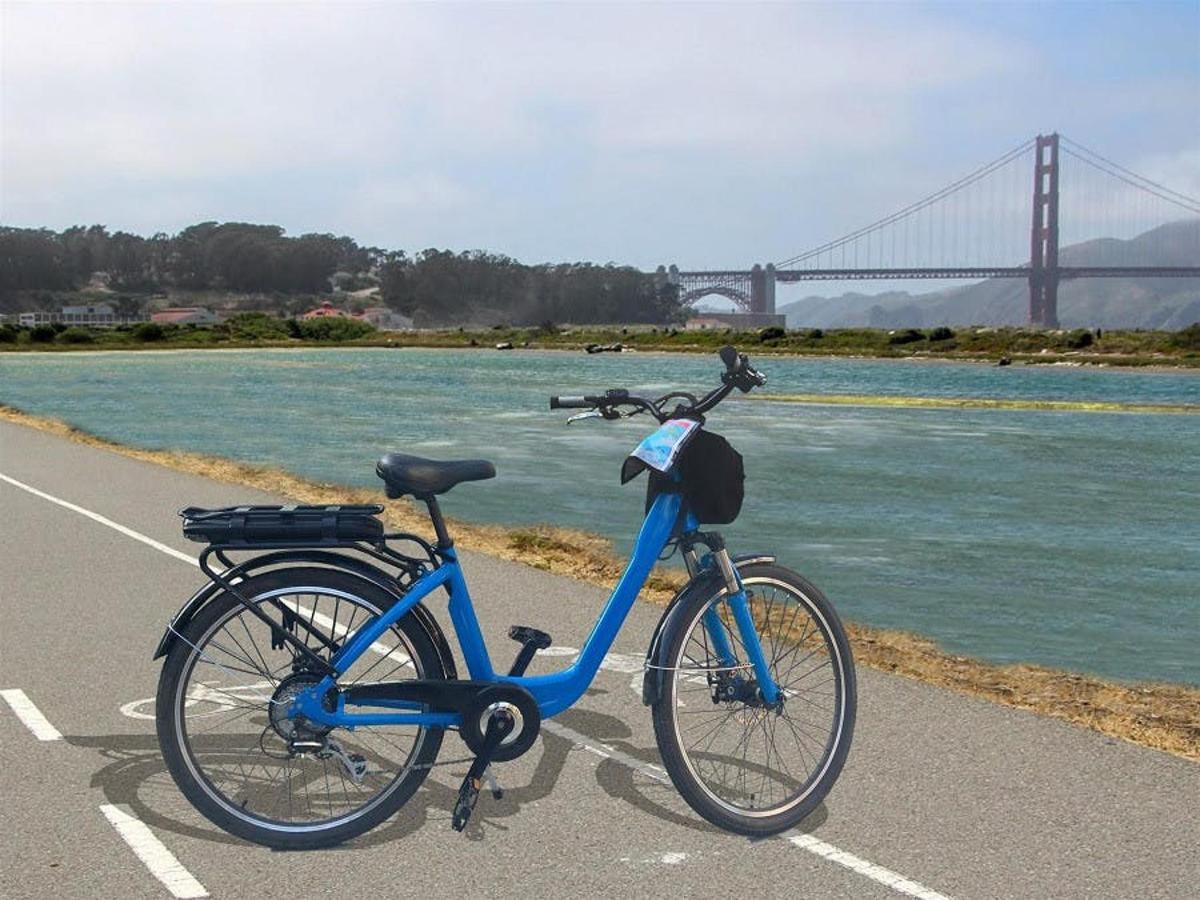 una bicicleta blava aparcada en un aparcament al costat d'un pont