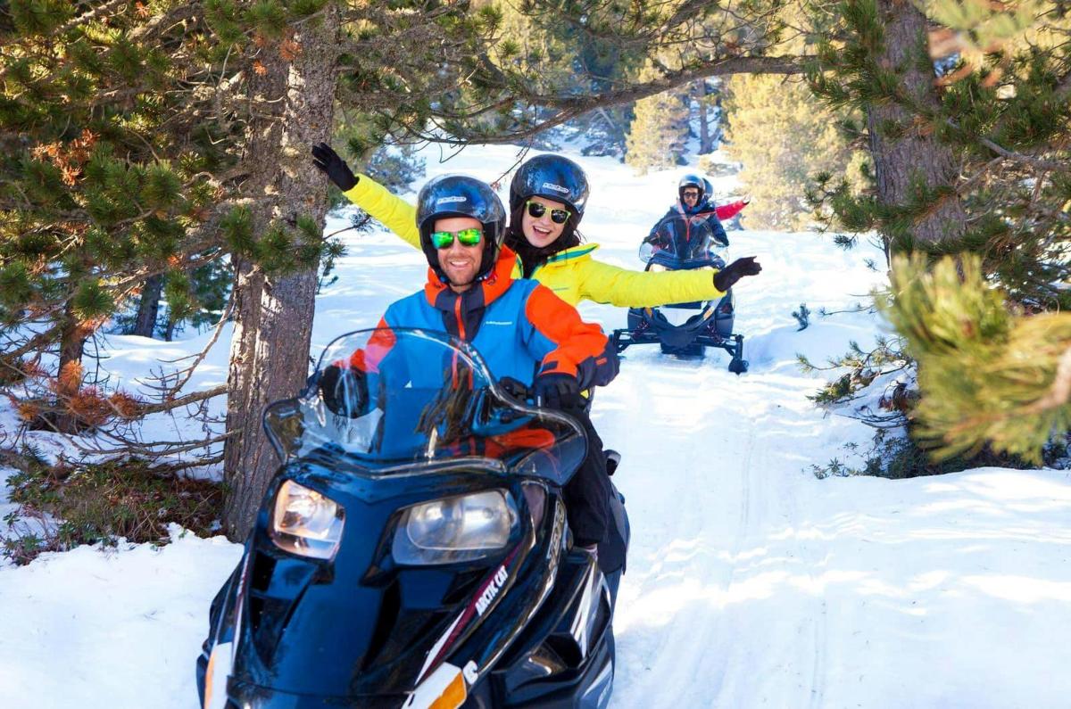 duas pessoas andando de snowmobile na neve