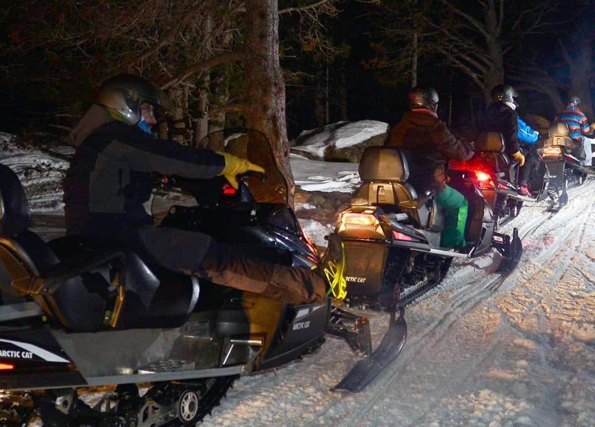 um grupo de pessoas andando de snowmobile na neve