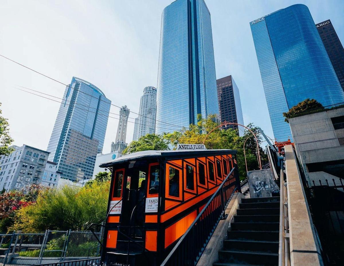 um trem laranja está viajando por uma cidade