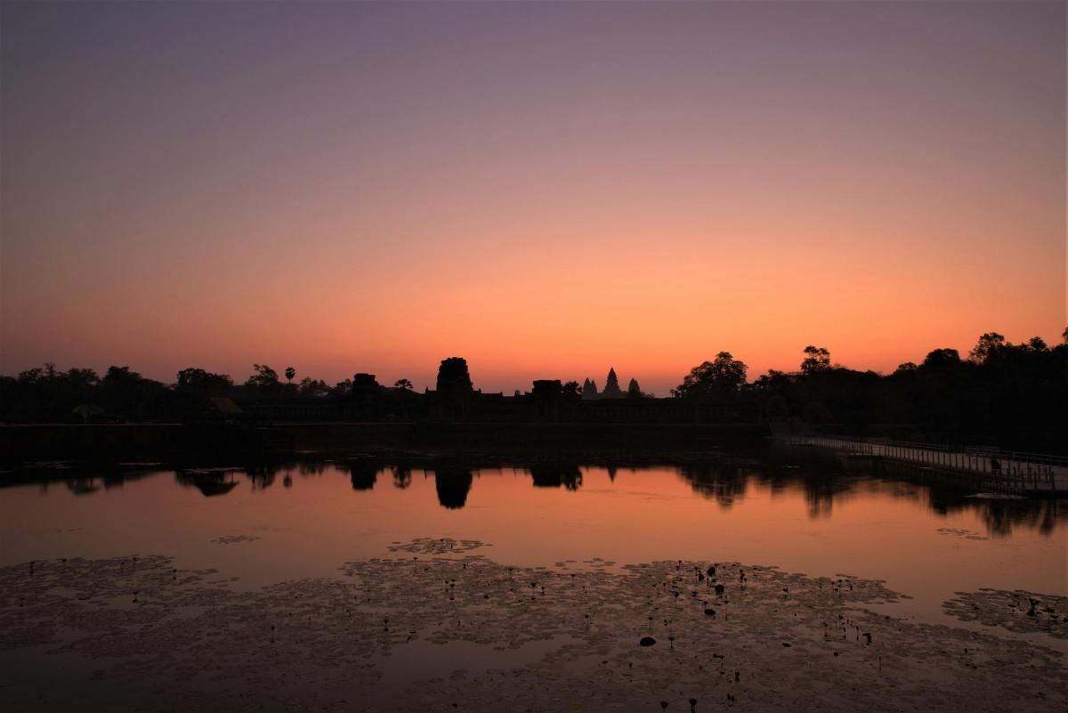 um pôr do sol sobre um lago com o pôr do sol ao fundo
