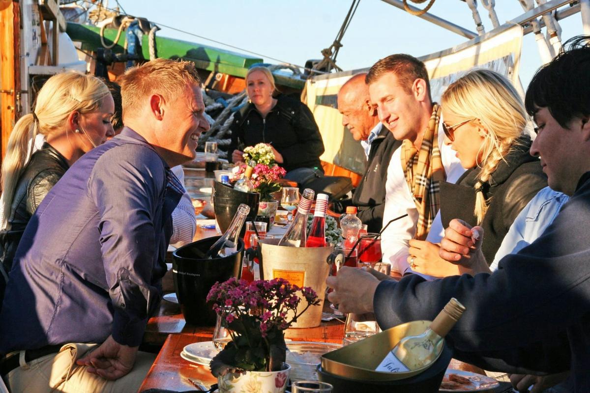 hópur fólks situr við borð með vínflöskum