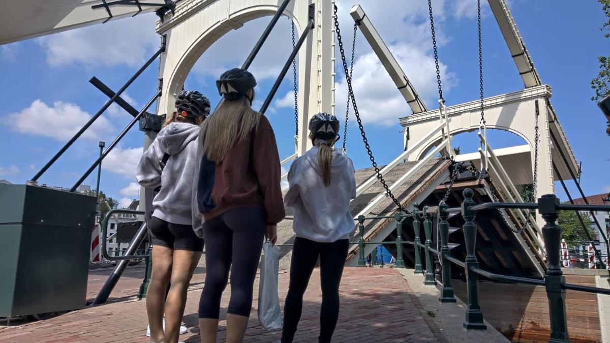 três meninas estão em um barco em uma ponte