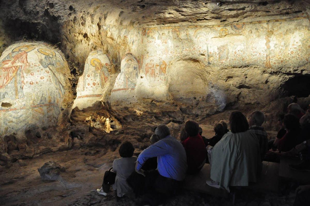 a group of people sitting in a cave looking at paintings