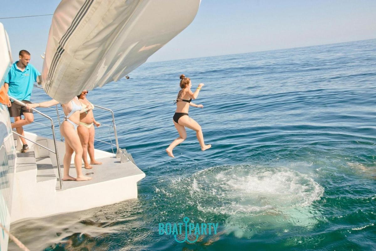 a group of people jumping off a boat in the water